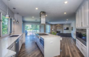 An open-concept kitchen with a living room in the background