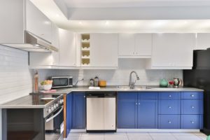 A kitchen designed with white cabinets and bright blue drawers.